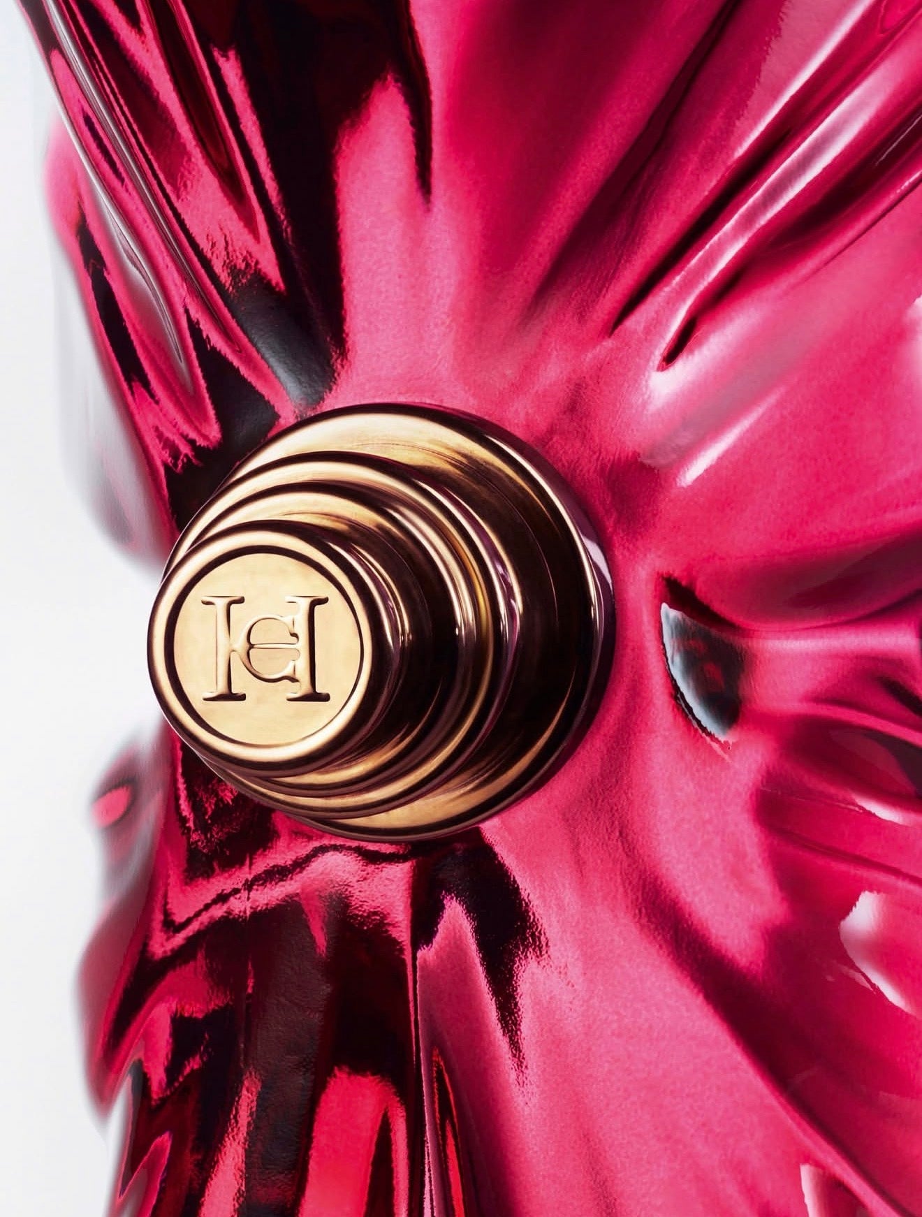 Close-up of a red Carolina Herrera bottle with a gold cap featuring a logo.