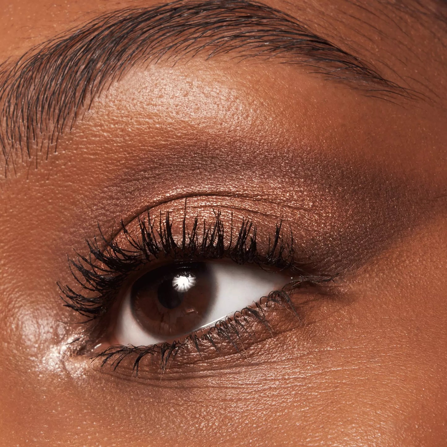 Close-up of a person's eye with bronze eyeshadow and eyeliner.