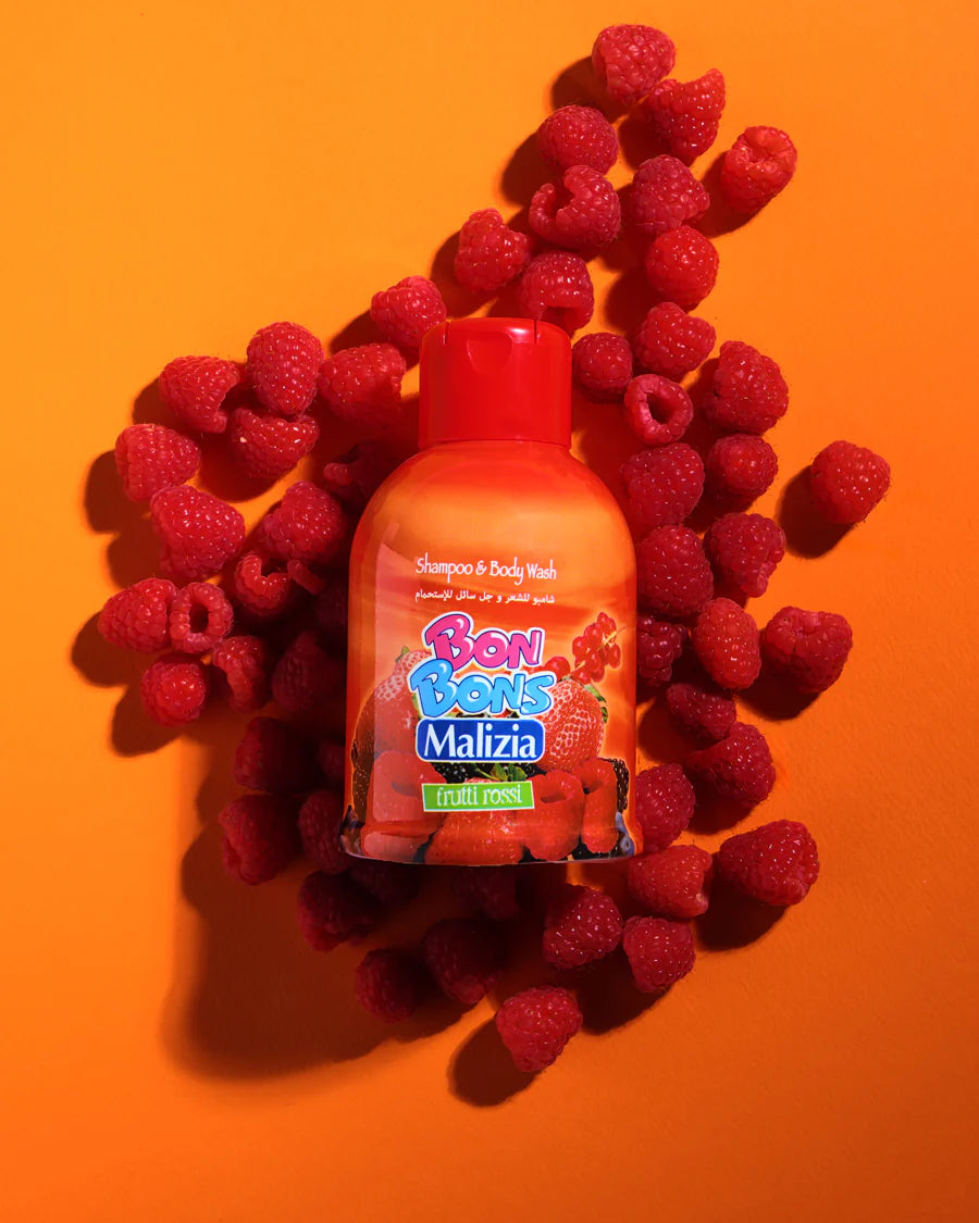 Bon Bons Malizia shampoo bottle surrounded by raspberries on an orange background