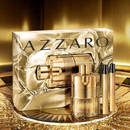 Gold Azzaro perfume set on a reflective surface with a gold background