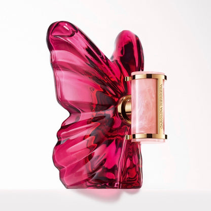 Pink butterfly-shaped Carolina Herrera La Bomba perfume bottle with gold cap on a white background