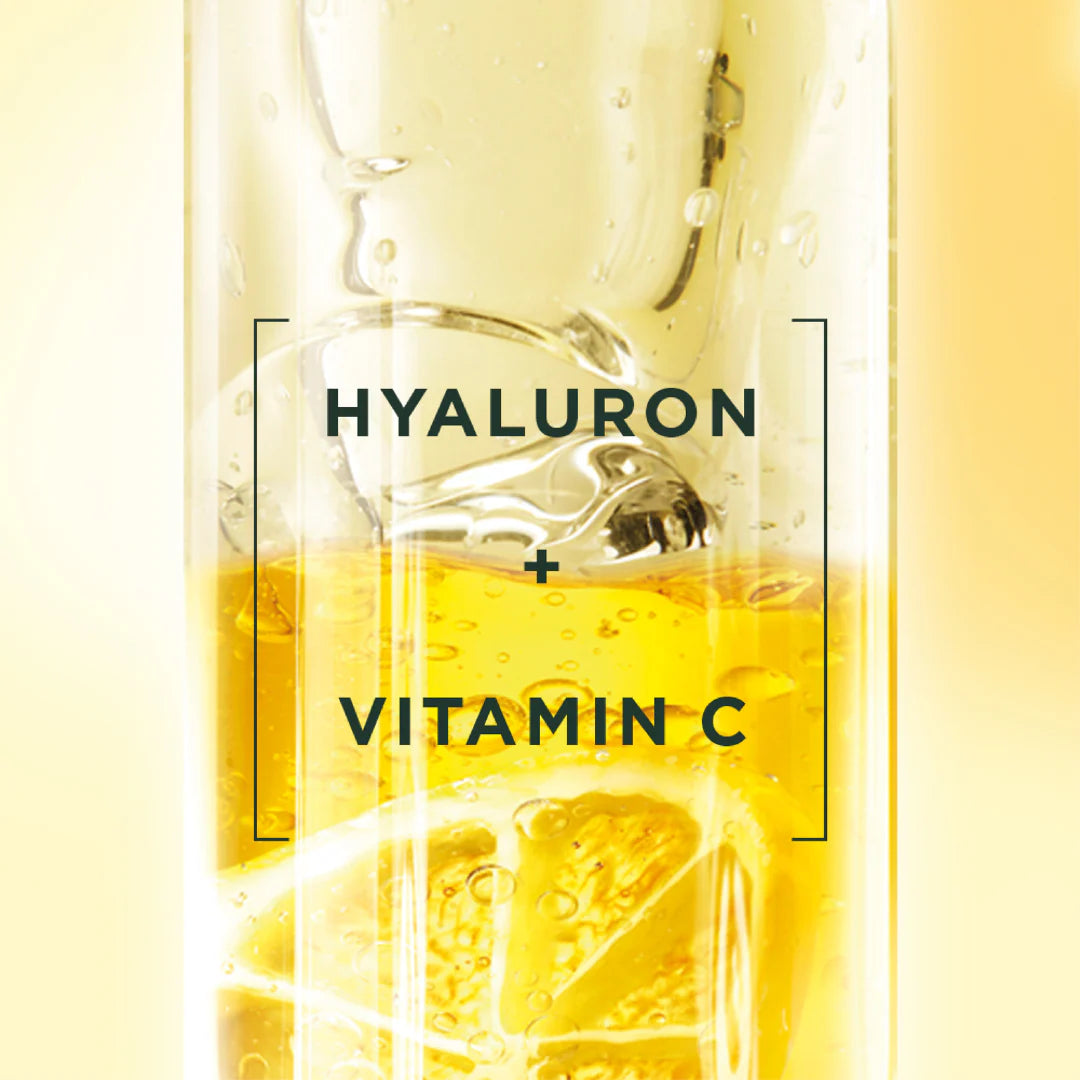 Glass of yellow liquid with 'Hyaluron + Vitamin C' text on a yellow background