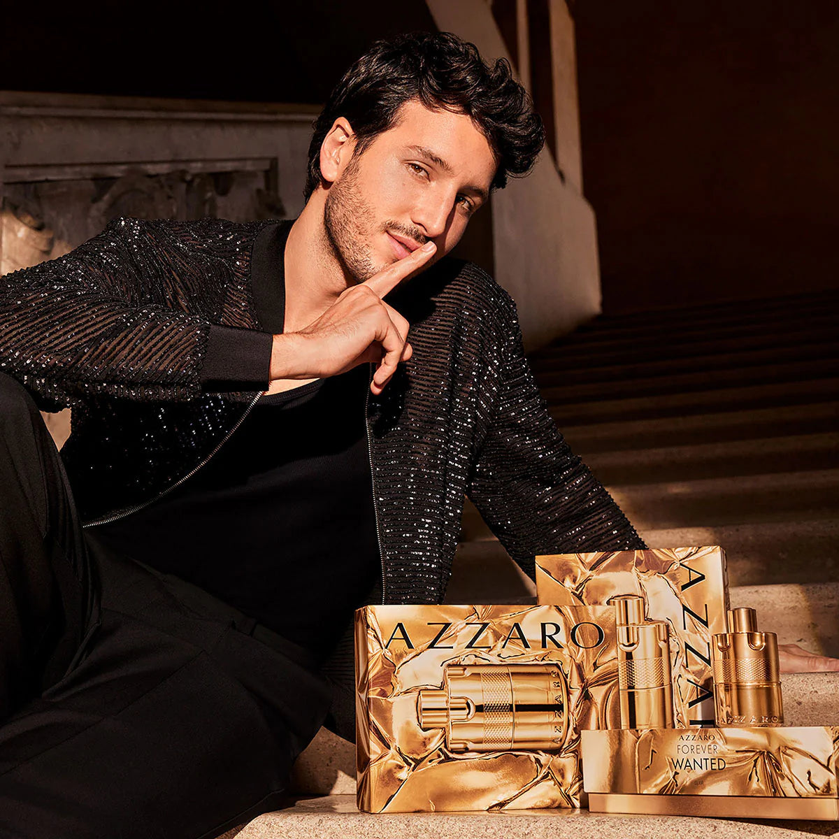 Man in a black sequined jacket with Azzaro perfume set on a table