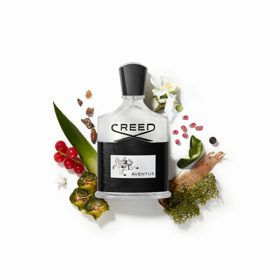 Creed Aventus perfume bottle surrounded by natural elements on a white background