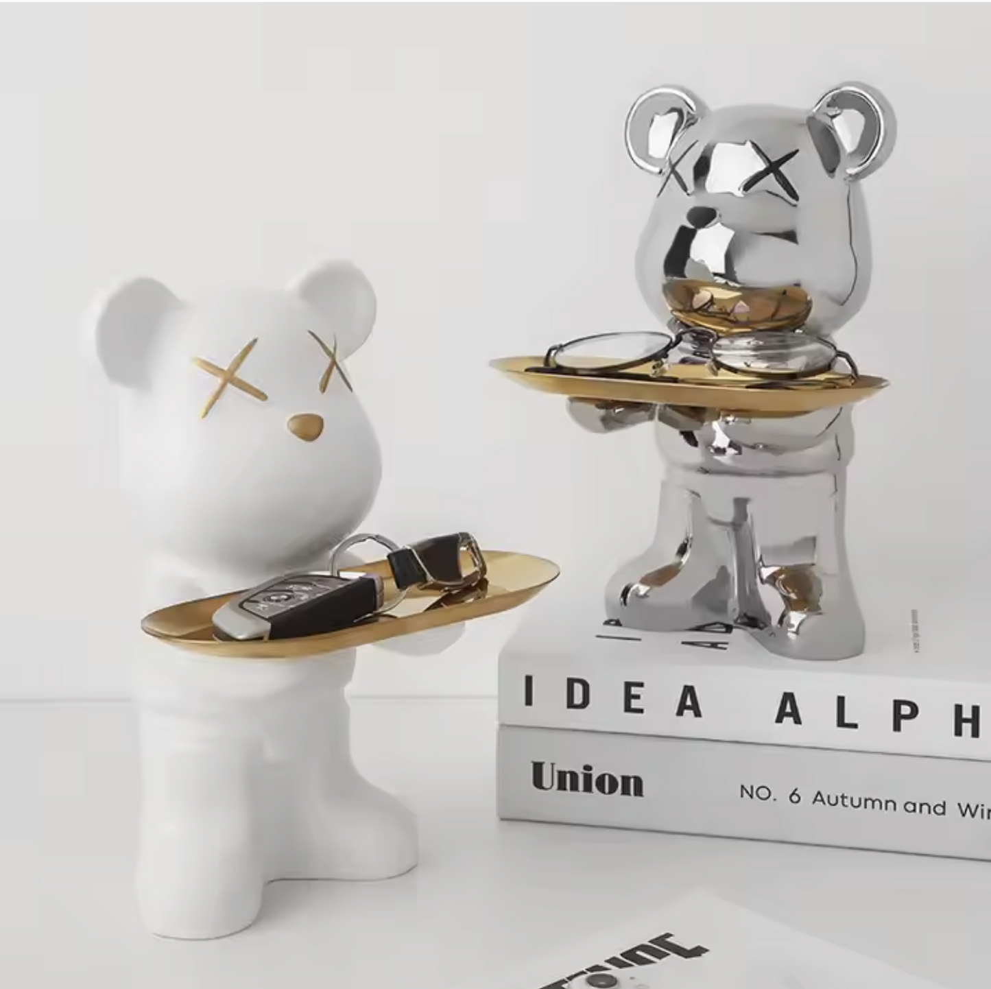 Two decorative bear figurines with gold accents on a white surface.