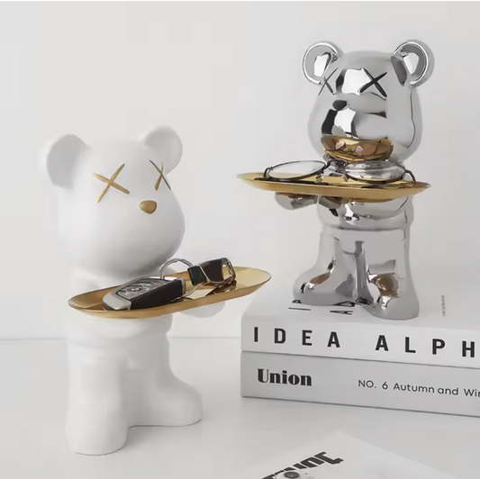 Two decorative bear figurines with gold accents on a white surface.