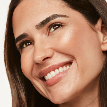 Close-up of a woman's face with a soft smile on a neutral background