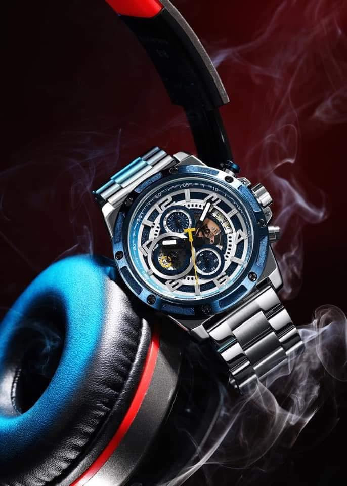 Luxury watch with detailed face and metal band, placed on a dark background with smoke effect.