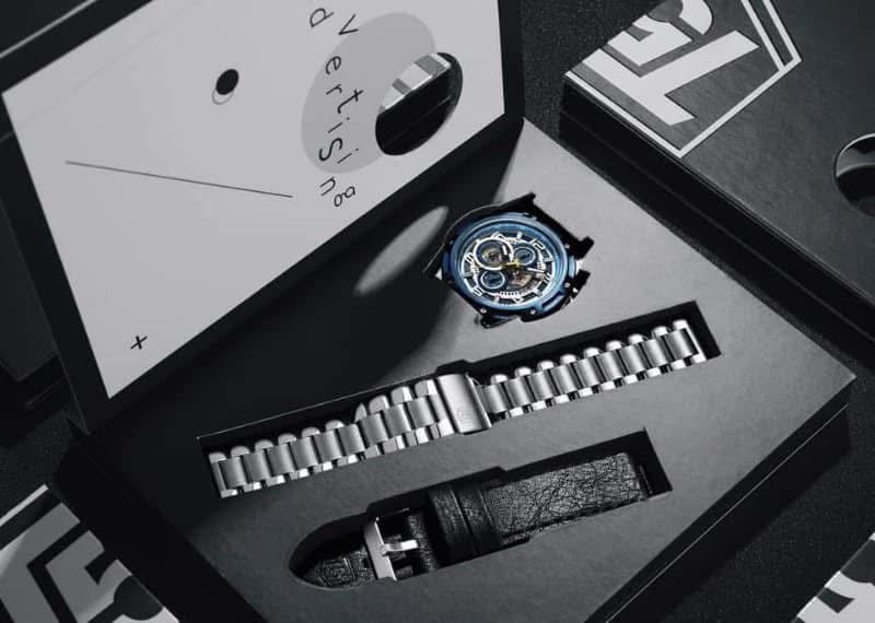 Watch with metal band in open black box, brand logo visible