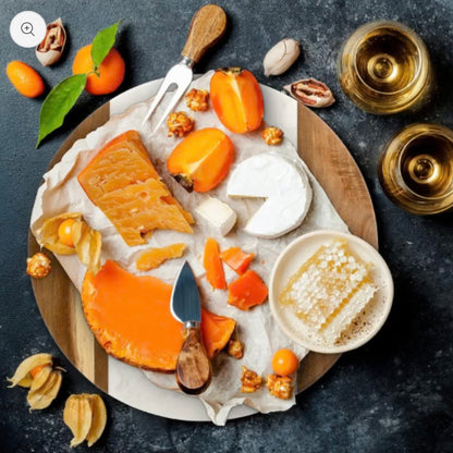 Assorted cheeses with fruits and honey on a marble and wooden board with a dark background