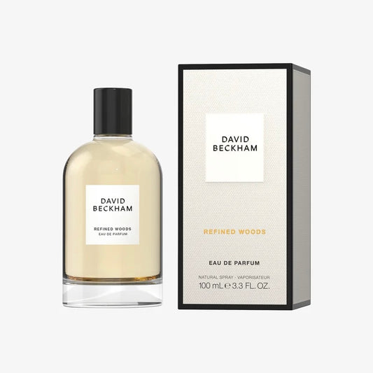 David Beckham Refined Woods Eau de Parfum 100ml bottle next to its textured cream-colored packaging box with black borders, on a light gray background.