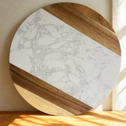 Round cutting board with marble and wood design on a wooden surface