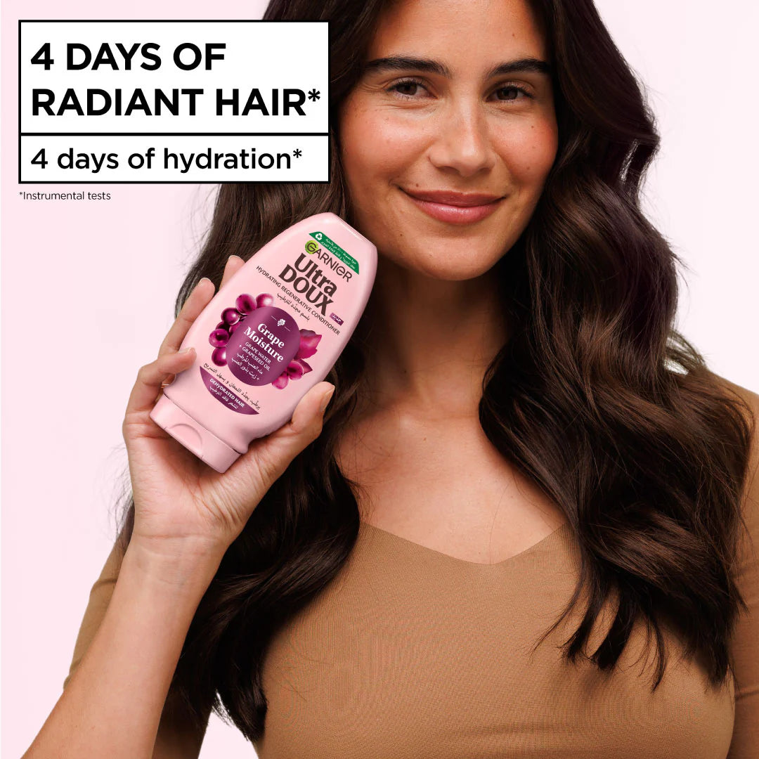 Woman holding a bottle of Ultra Doux shampoo with text about radiant hair and hydration.