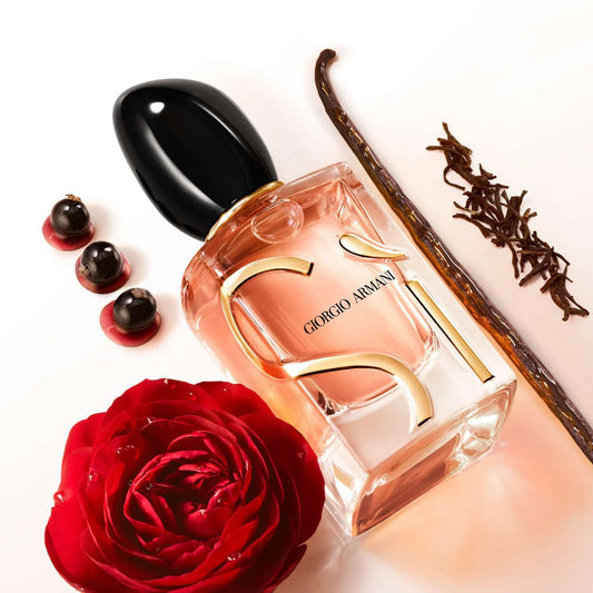 Giorgio Armani Si perfume bottle with a red rose, vanilla bean, and berries on a white background