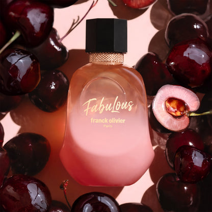 Perfume bottle labeled 'Fabulous' surrounded by cherries on a pink background